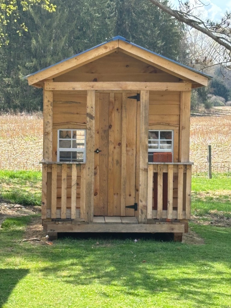 Small wooden storage shed with front porch and windows